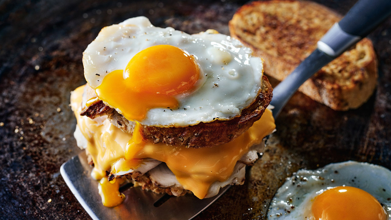 Sandwich grillé au fromage et à la dinde garni d’un œuf frit
